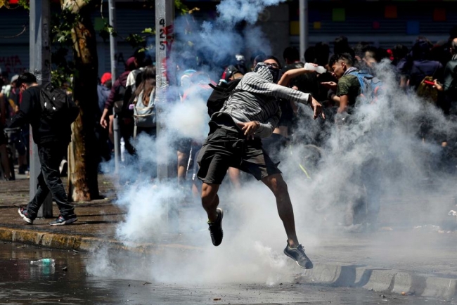 Göz yaşartıcı gaz kapsülünü, polise geri atan protestocu / Fotoğraf: AP
