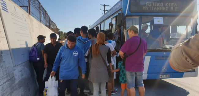 Morya mülteci kampı sakinleri kamp önünden geçen otobüslerle adaya iniyor.