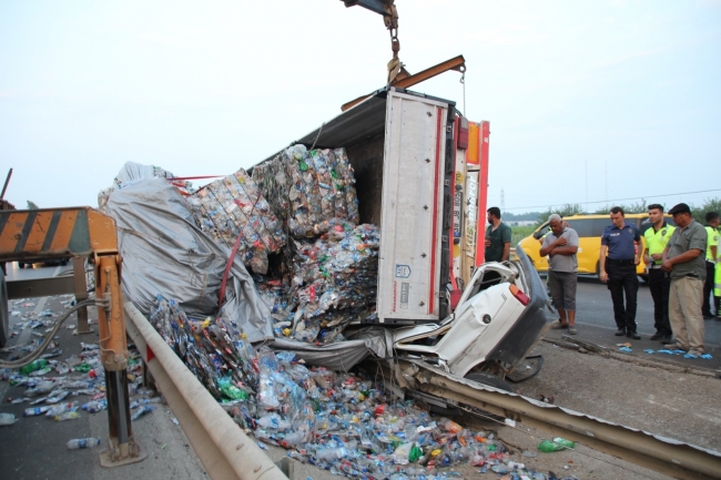Lastiği patlayan tır otomobilin üzerine devrildi