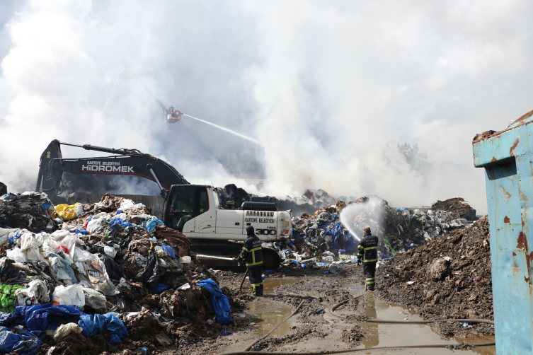 Kocaeli'deki geri dönüşüm fabrikasında çıkan yangında ekipler, atıkları iş makinesi yardımıyla ayrıştırıyor. Kaynak: AA