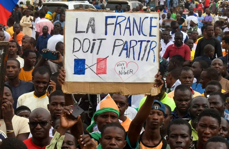  Göstericiler, Fransa'nın ülkeyi tamamen terk etmesi gerektiğine dair pankartlar taşıyor. 