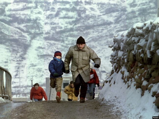 Keskin nişancıları atlatmak için koşan bir baba ve oğlu. Dobrinja, Saraybosna, 4 Ocak 1993. | Fotoğraf: AFP 