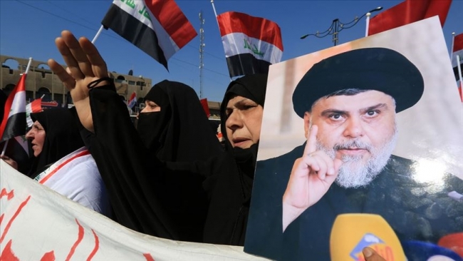 Irak'taki Sadr Hareketi lideri Mukteda es-Sadr'ın fotoğrafını taşıyan protestocu bir kadın. Fotoğraf: AA